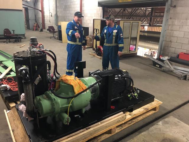 Two service techs standing next to a large industrial pump.