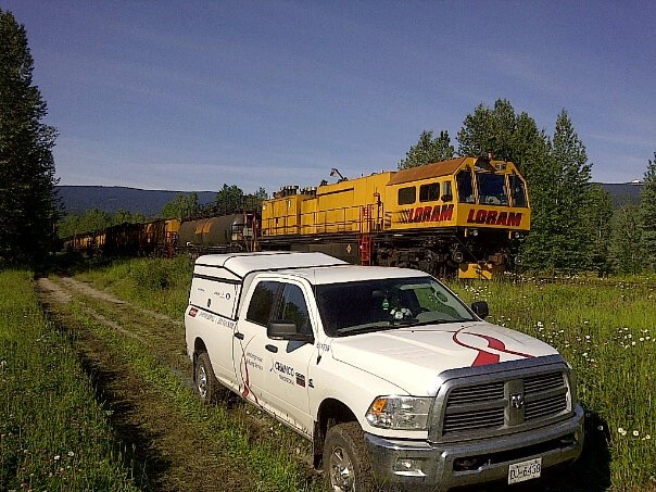 Loram service A Chamco service truck in a field with a train behind.
