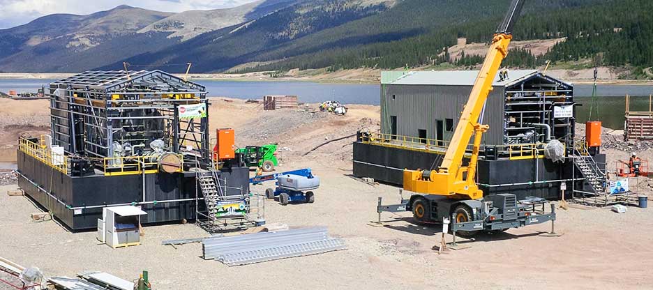 Two pump houses being constructed with a crane.