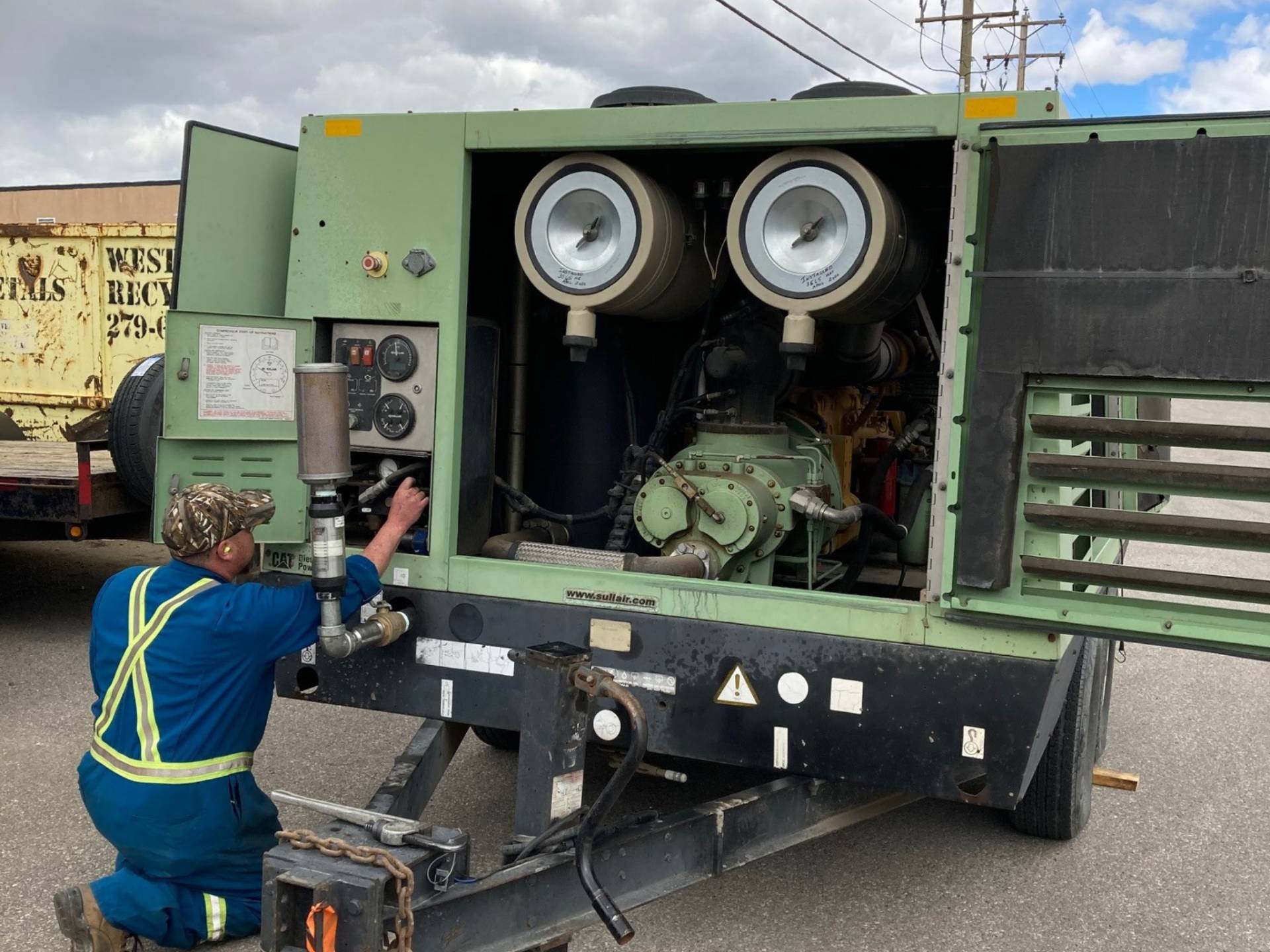 A technician servicing a Sullair portable air compressor