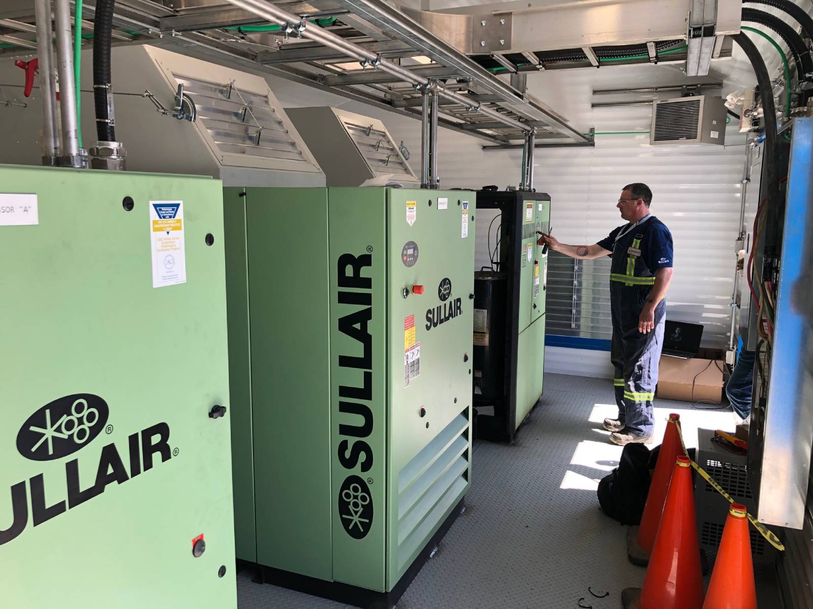 An air compressor system with a technician working on the one air compressor.