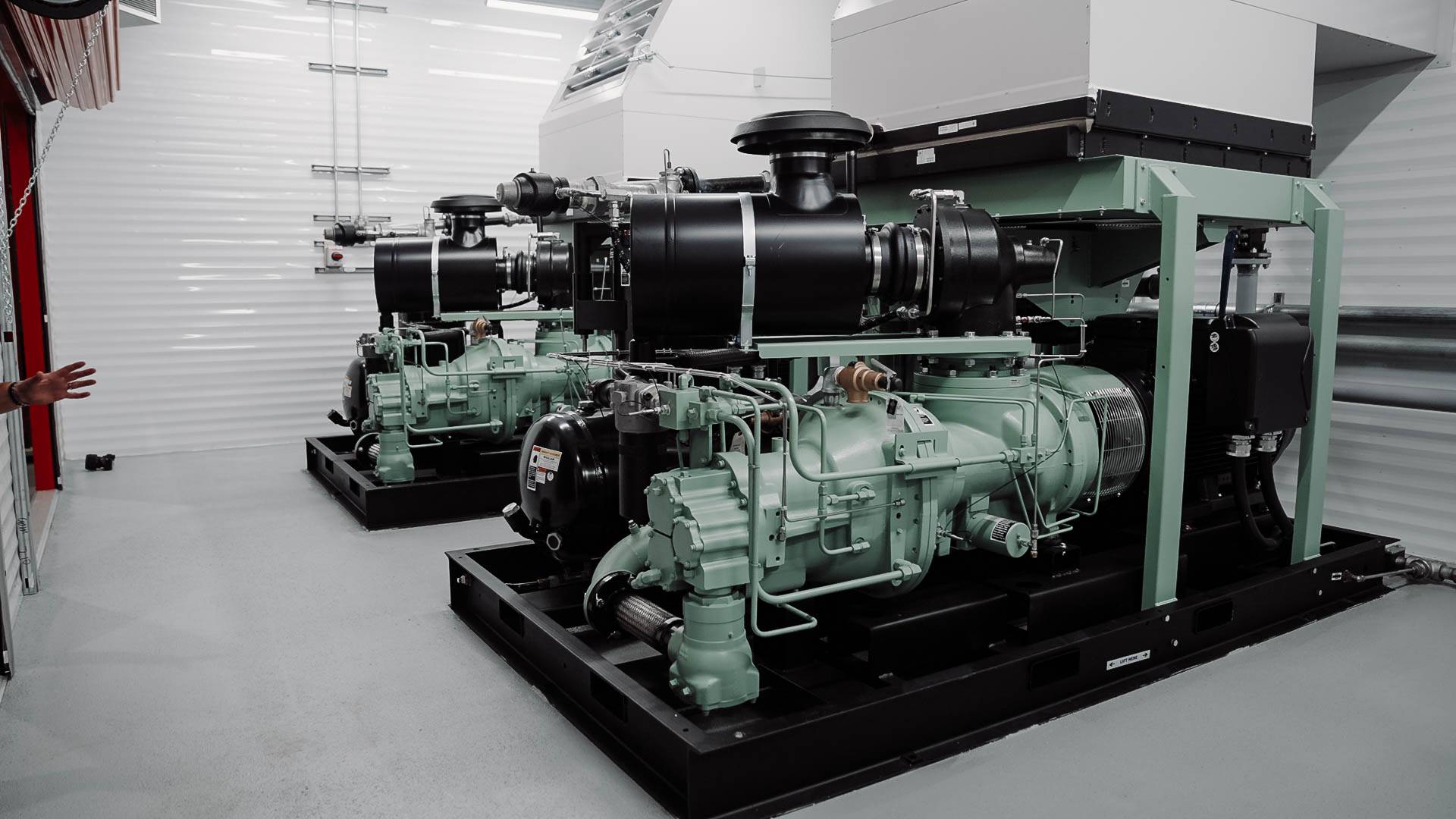 Two large industrial air compressor units installed in a mechanical room, illustrating the type of equipment discussed in the blog "How to Select the Right Industrial Air Compressor."