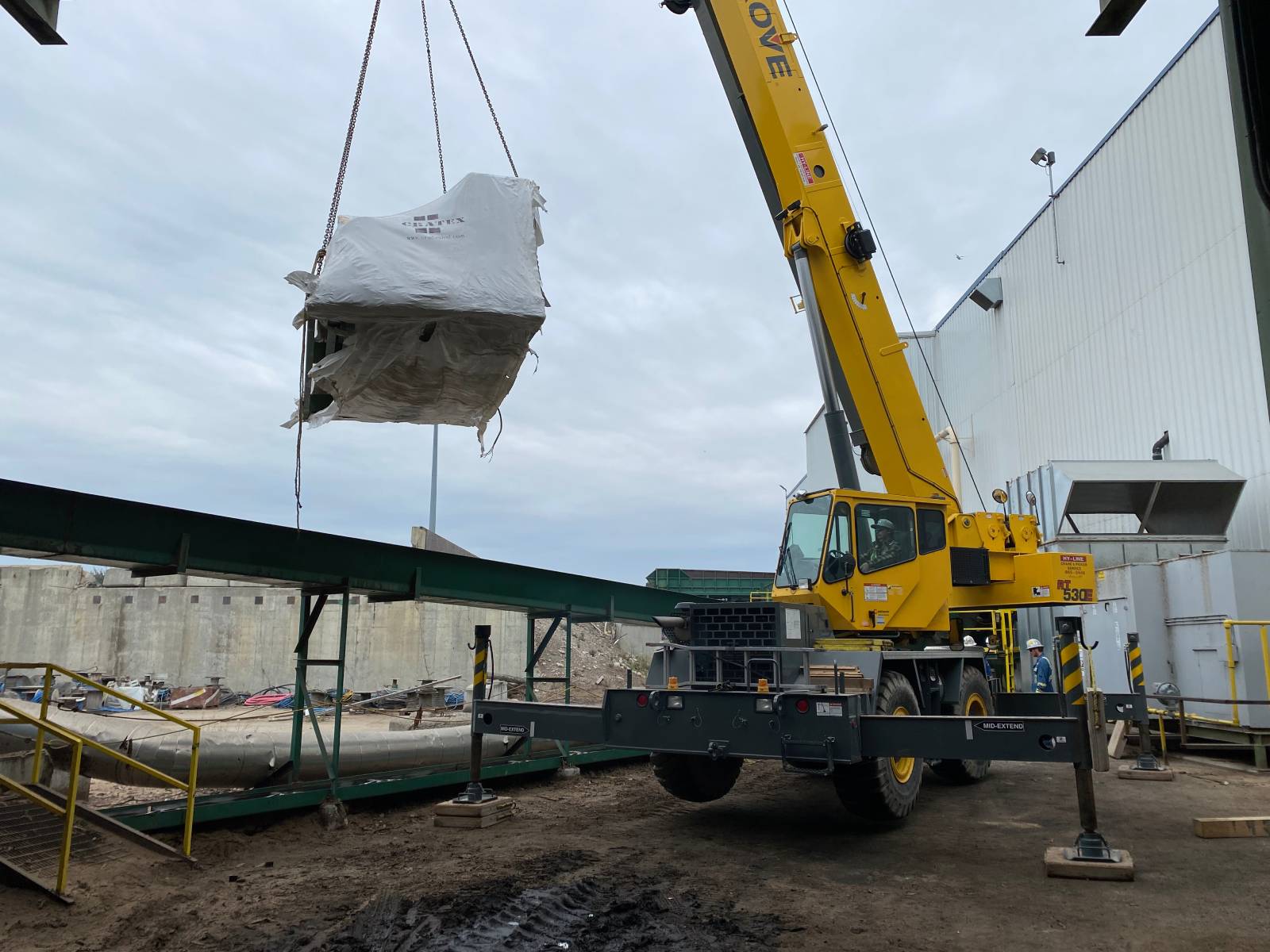 Lifting-Compressed-Air-System Crane lifts a compressed air system component from a truck for Alberta sawmill project.