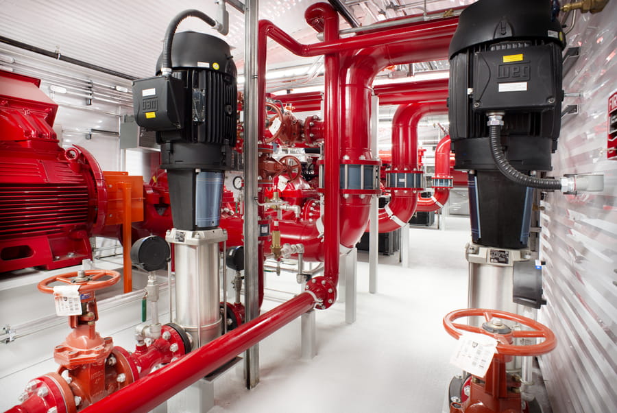 LNG_Fire_Pump_3-VMz80sjs Interior of a Chamco fire pump package showing red piping, electric motors, and jockey pumps with an open floor plan designed for equipment access and maintenance.
