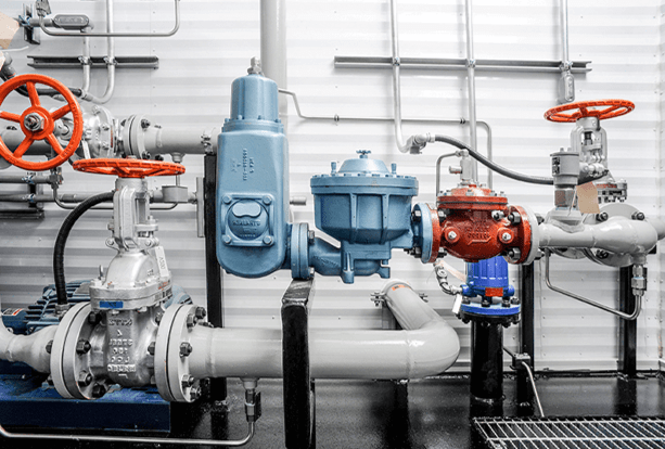 Industrial piping with silver and red wheel-handle valves, a blue pressure regulator, and interconnected pipes